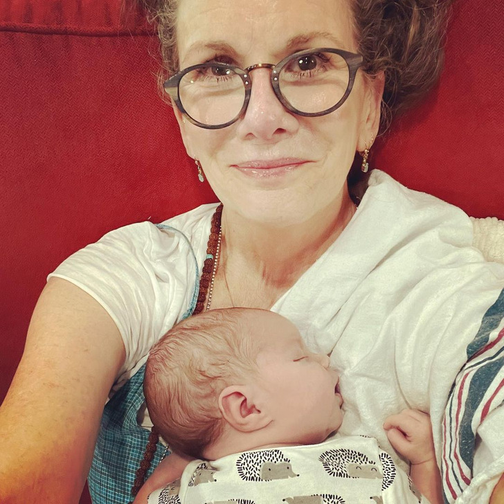 Melissa Gilbert wearing glasses holding a baby on her lap.