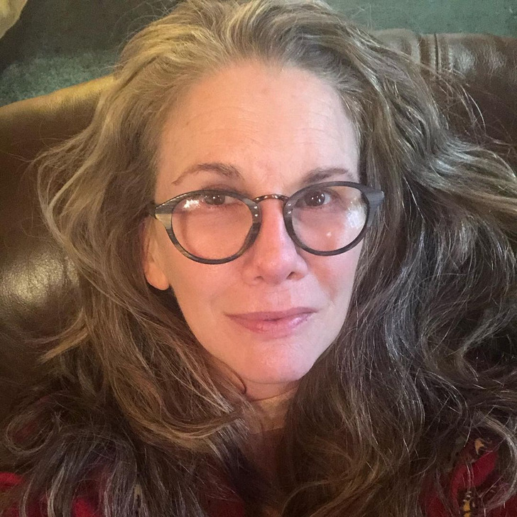 Melissa Gilbert, wearing glasses, takes a selfie sitting on a brown leather couch.