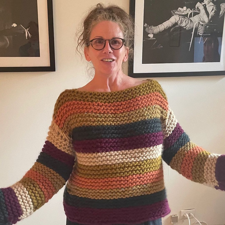 Melissa Gilbert wearing a colorful stripped crochet sweater in front of black and white photos.