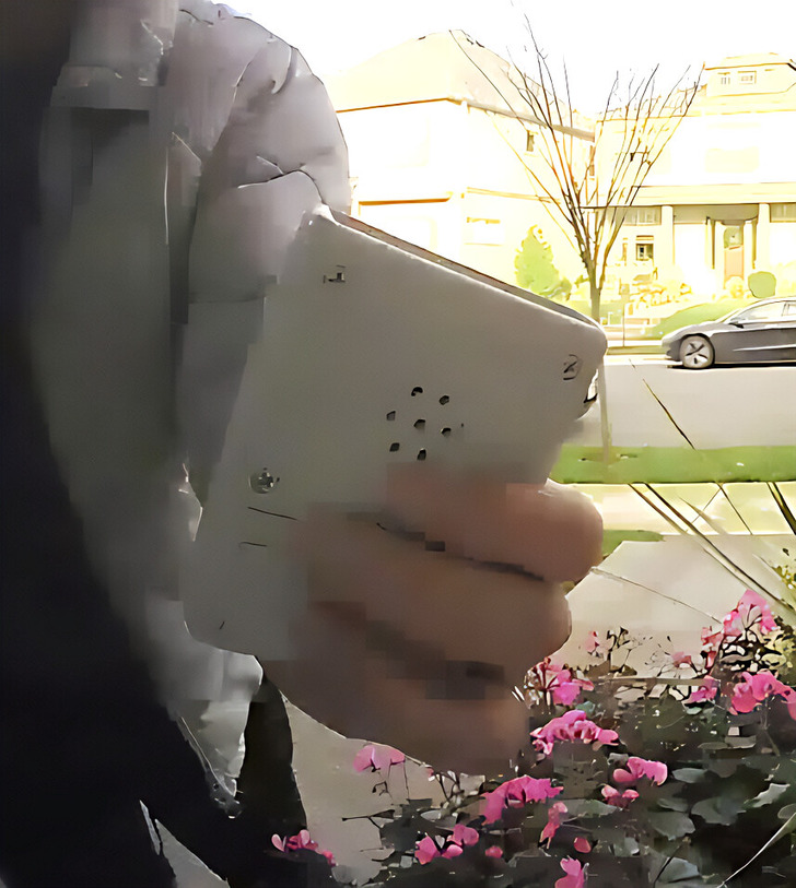 Closeup of a person holding a device, drive way in the background.