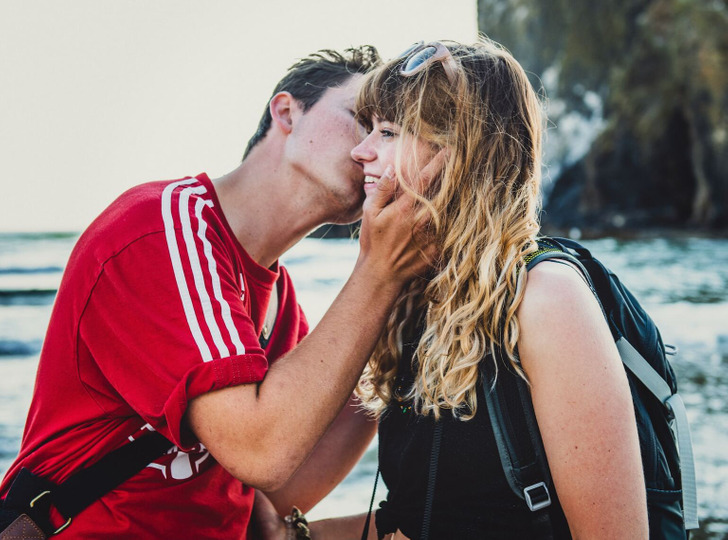 A man kissing the cheek of a woman while cupping her face.