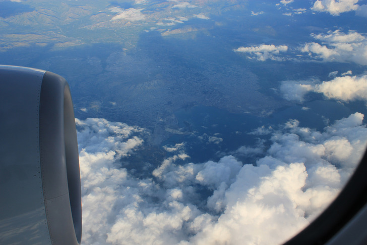 View of clouds and landscape from an airplane window.