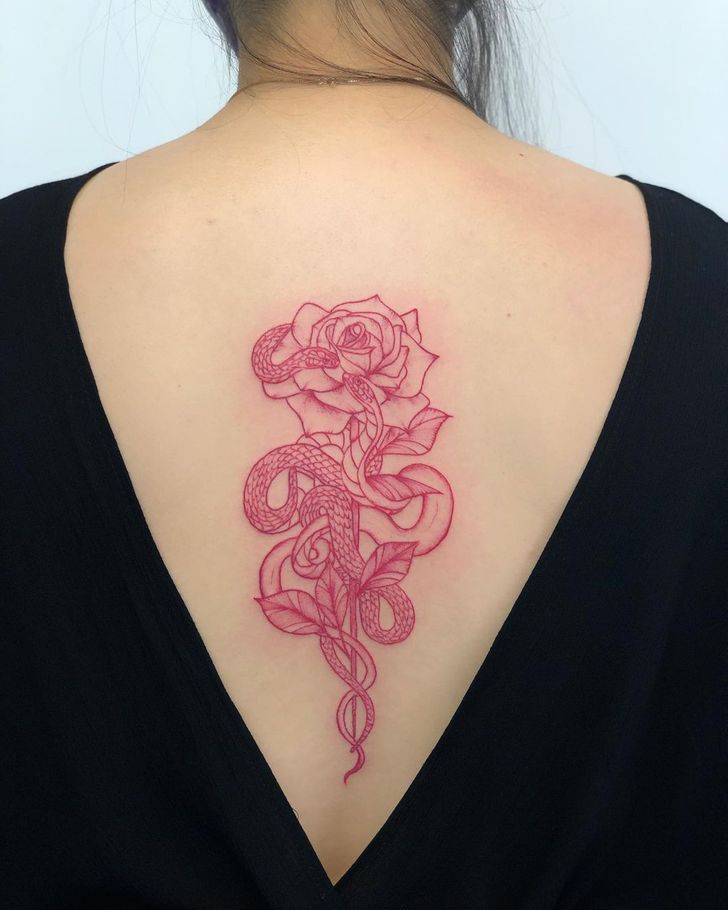 Red ink heart outline tattoo behind the left ear