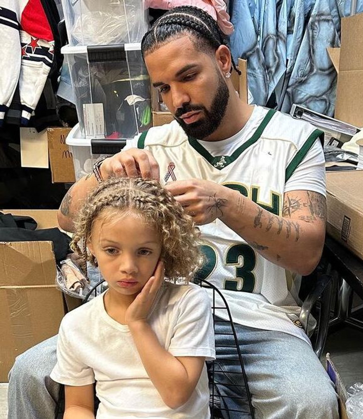 Drake wearing sport clothes brading his son's blonde hair.