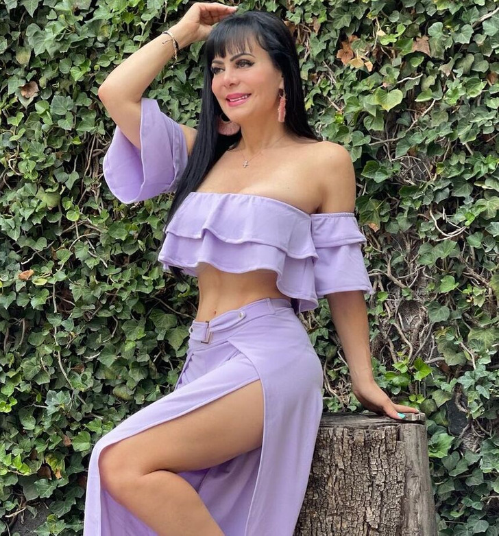 A brunette model posing for a photo in the garden wearing a lilac gown and pink high heels.