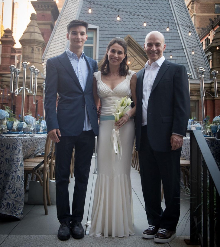 A brunette bride wearing her wedding gown together with two men in suits.