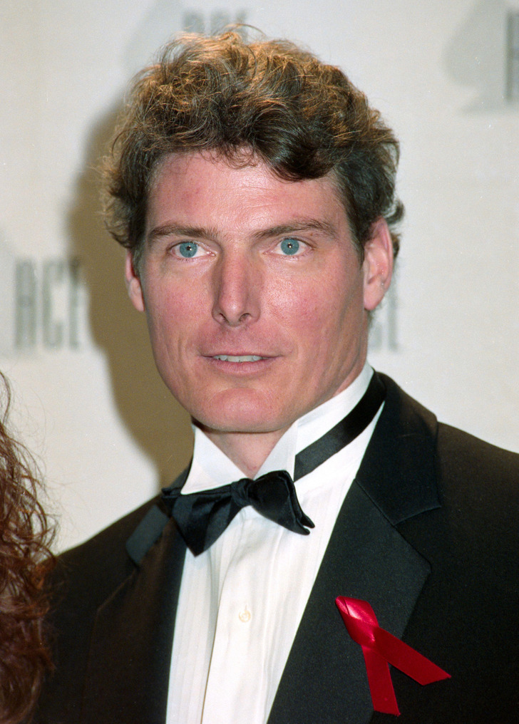 Christopher Reeve wearing a black suit and bow tie with a red cancer ribbon
