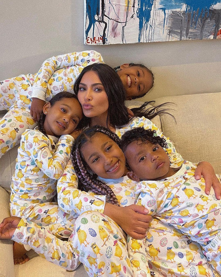 Kim Kardashian pouts on a couch with her four kids in matching night suits.
