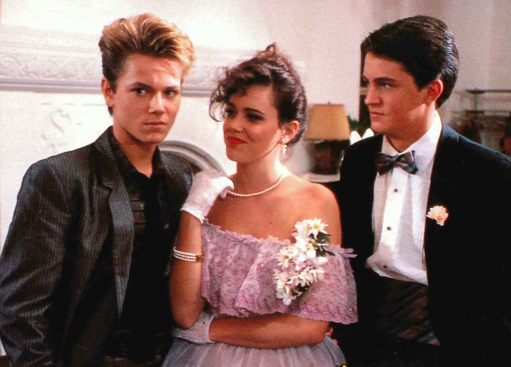Two young men wearing suit and tie and a young woman wearing a pink prom dress.