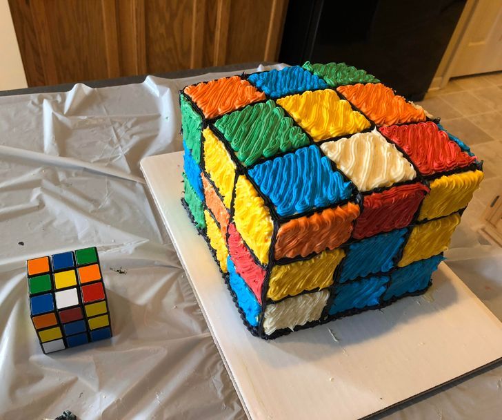 A magic cube cake besides a real magic cube.