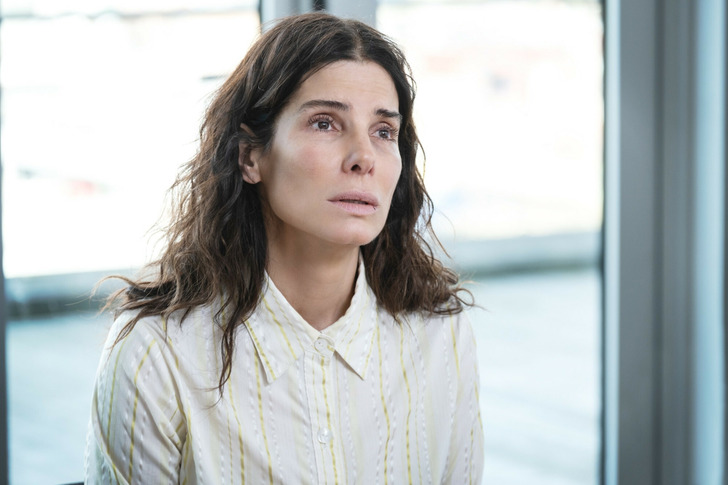 A make-up free Sandra Bullock in a white shirt with yellow stripes.