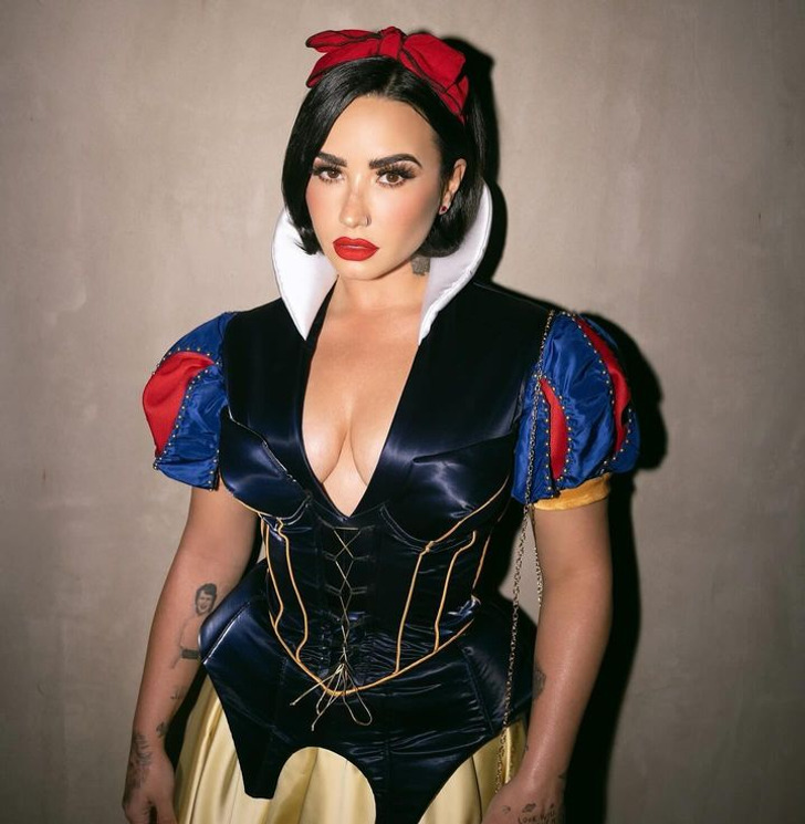 Singer Demi Lovato in a blue corset top and yellow skirt with a big red ribbon on her head.