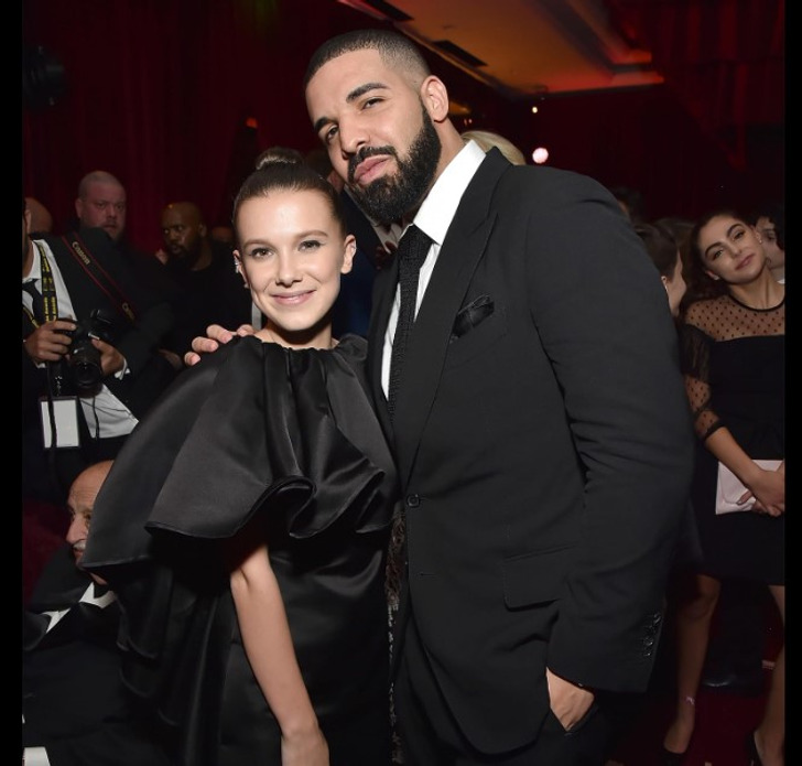Millie Bobby Brown and Drake both wearing black clothes.