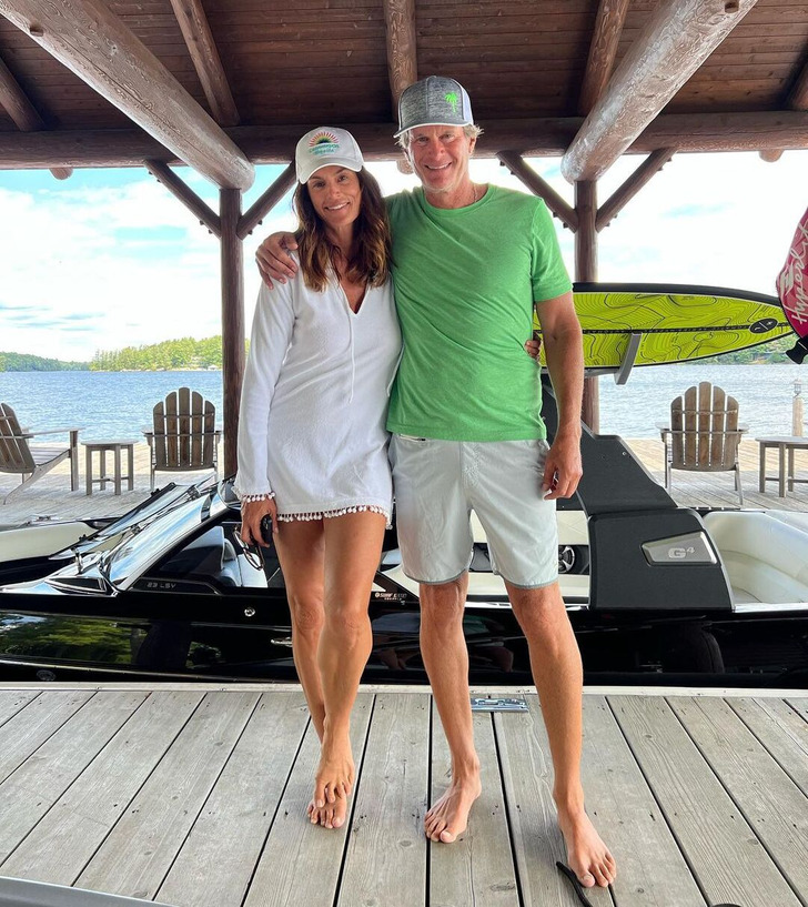 Cindy Crawford and husband on the pier at the beach, wearing caps.
