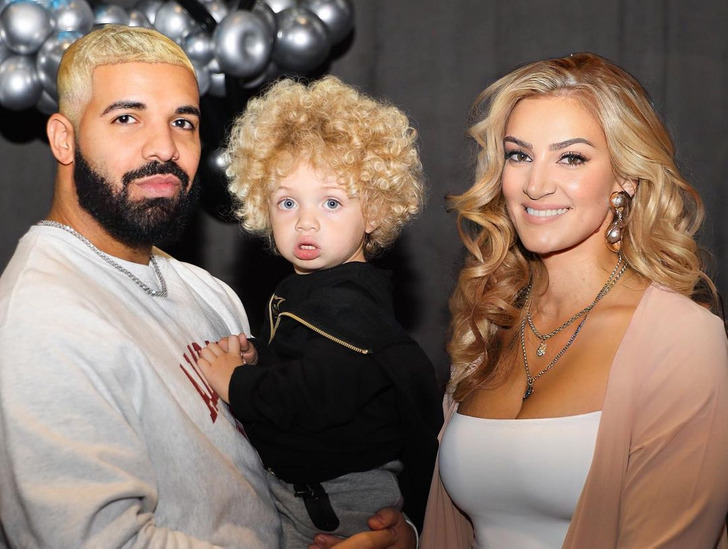 Drake with blond hair holding his son together with the mother of his son.