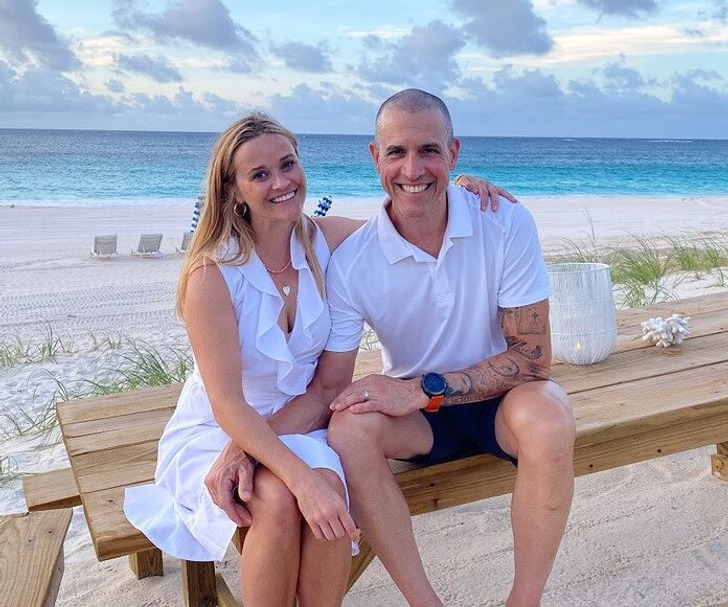 Reese Witherspoon with Jim Toth, sitting on a wooden table by the beach.