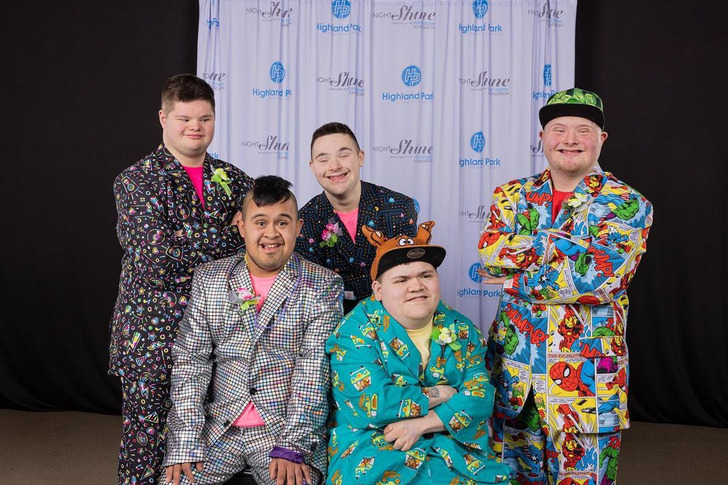 Five men with Down syndrome wearing colorful printed suits.