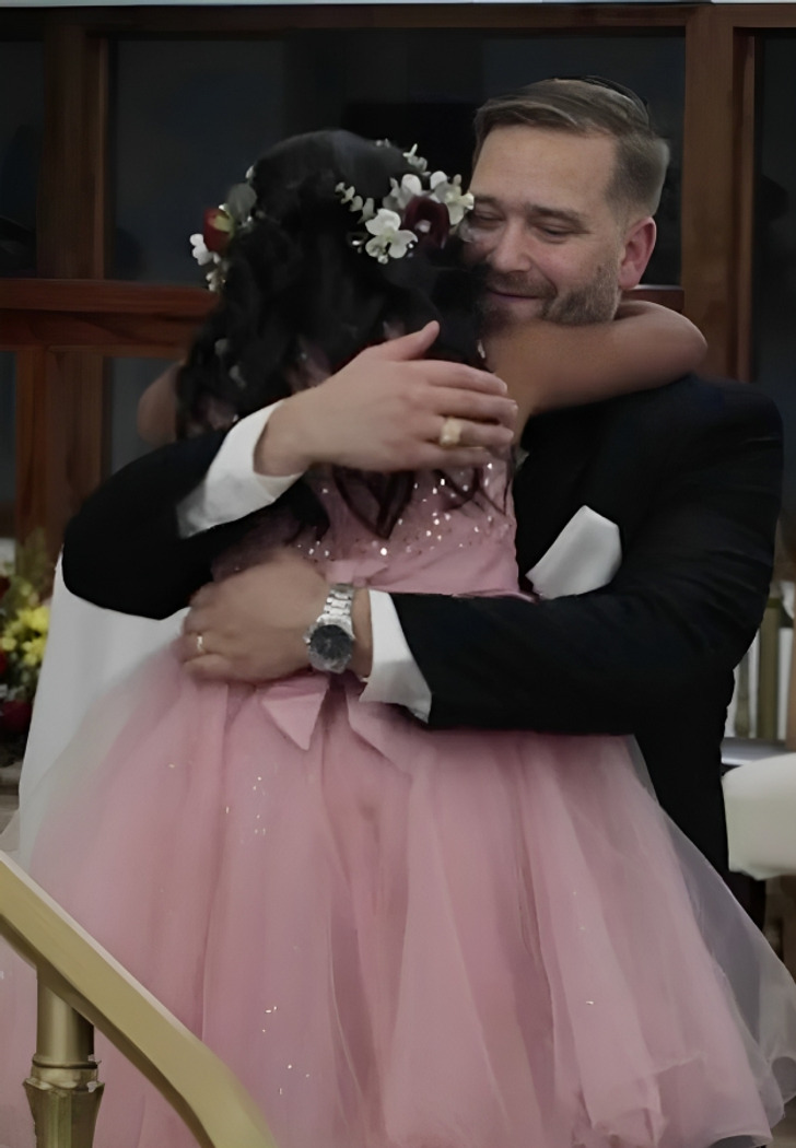 A man embracing a girl wearing a pink dress.