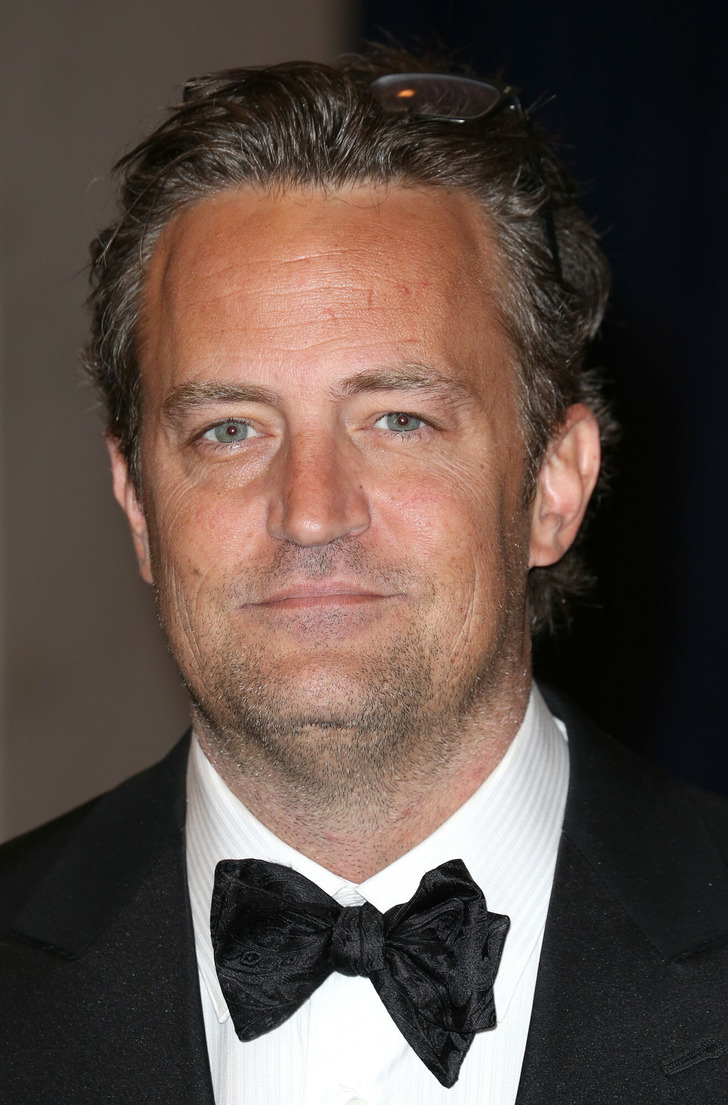Matthew Perry wearing a black suit and black bow tie.