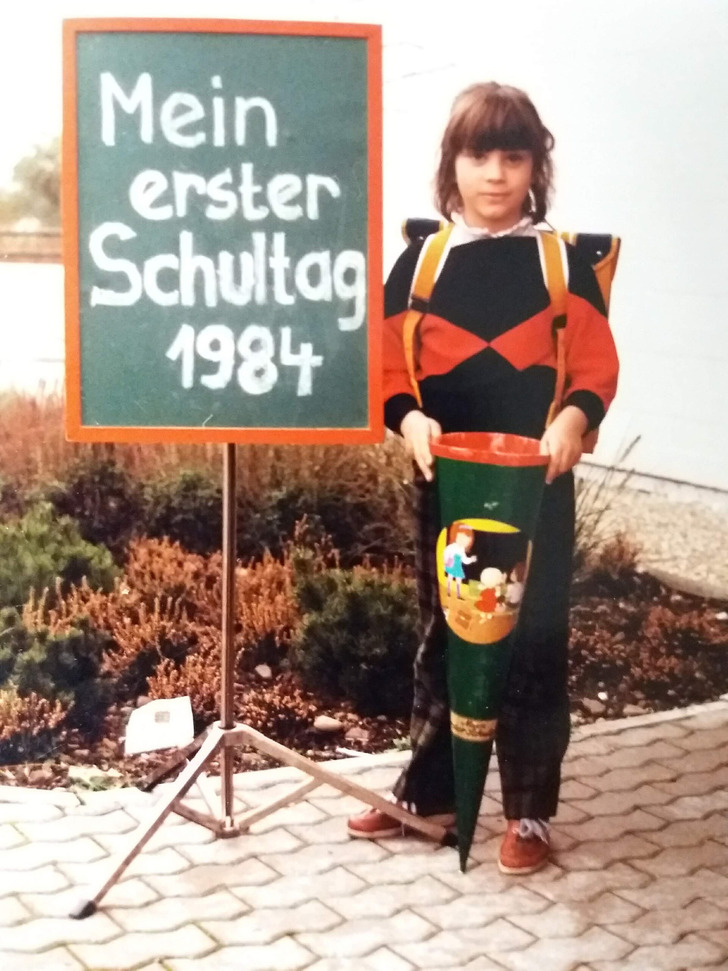 A first grader with her Schultüte and a chalkboard sign, Germany, 1984