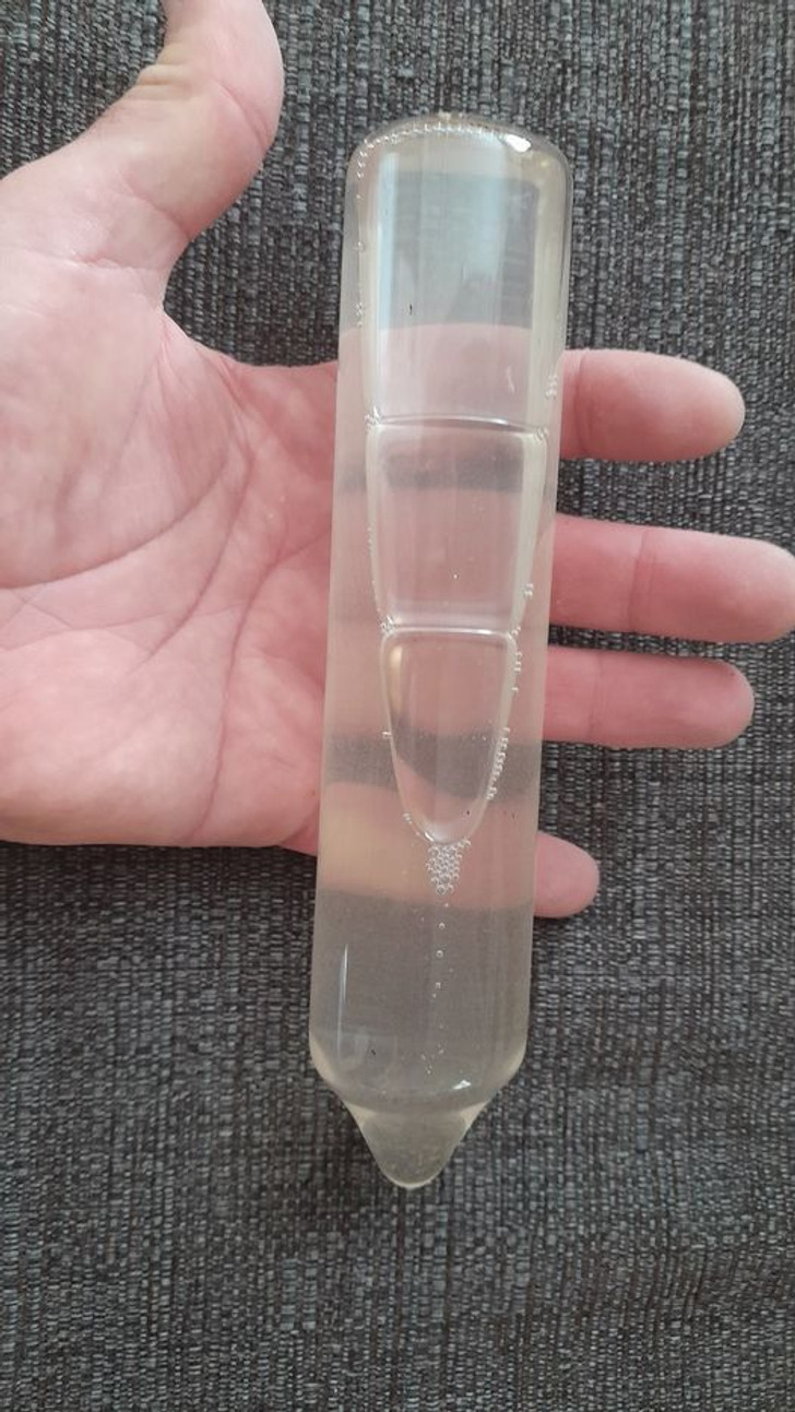 Closeup of a hand holding a plastic bottle with clear liquid, no markings.