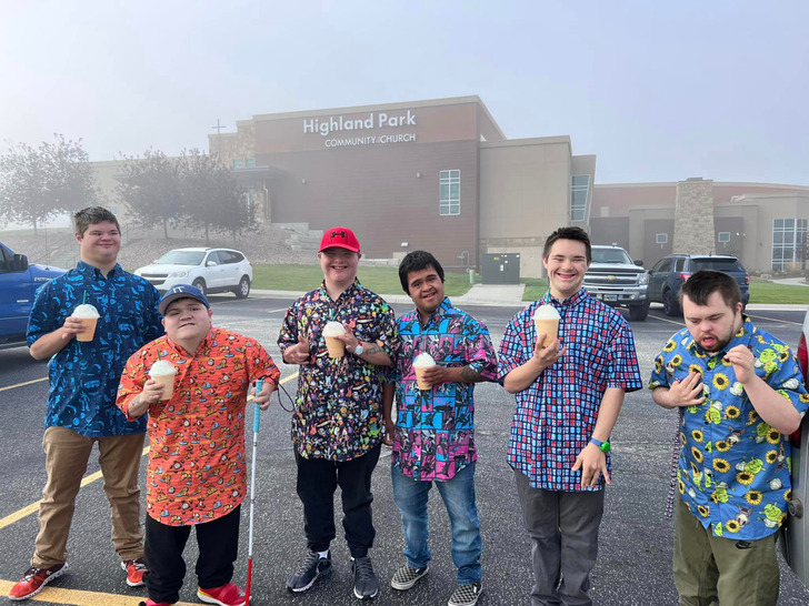 Six young men with Down syndrome holding iced-coffee on their hands.