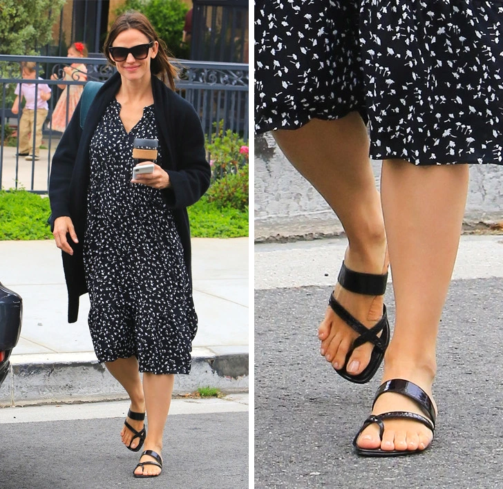 Jennifer Garner in a dress and sunglasses with sandals that show her toes, walking outside.
