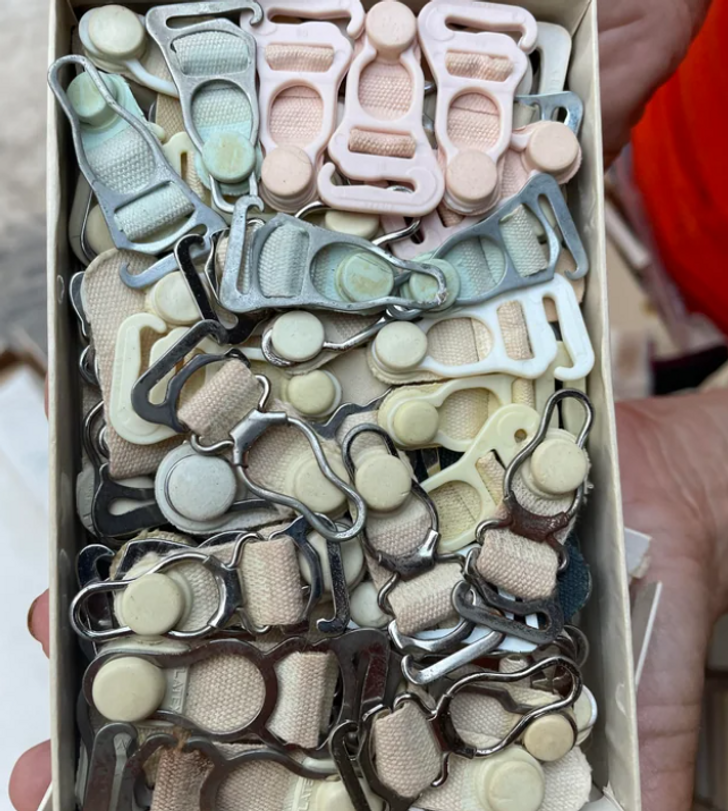 Closeup of a box of old, various colored plastic clasps being held in a palm.