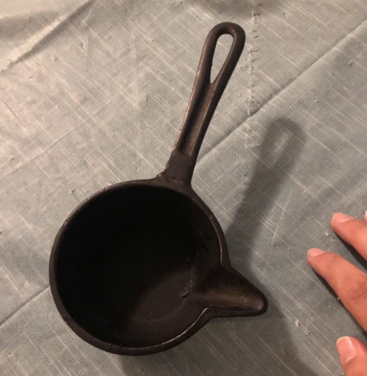 A black cast iron pan with an off-centre groove, casting a shadow.