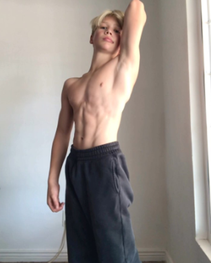 Young blond boy, shirtless, shows his belly muscles.
