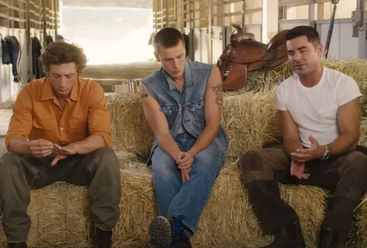 A group of young men sitting on hay bales in a stable.