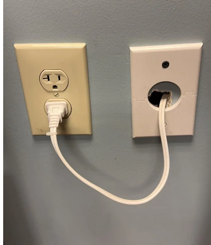 A wire coming out of a wall and plugging in a socket.