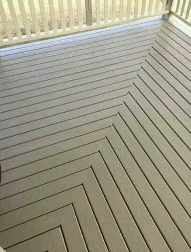 Tan wooden deck with diagonal plank design and railing.