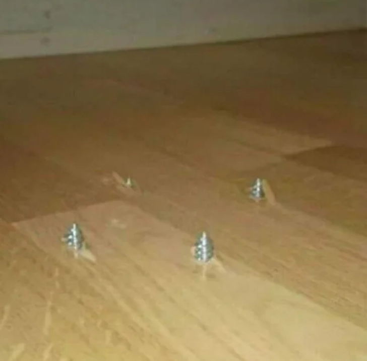 Four screws on a floor.