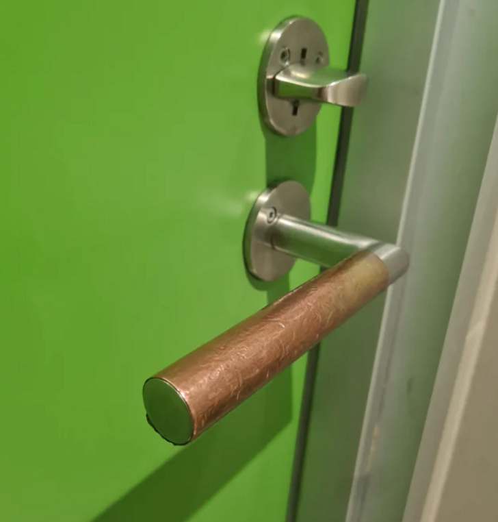 A green door with a closeup on its handle covered in a brown coating.