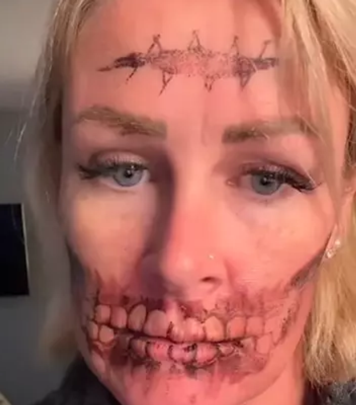 Woman looking sad with a skull tattoo on her face.