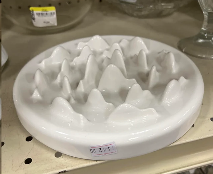 White plates with spikes at the top sitting on a shelve.