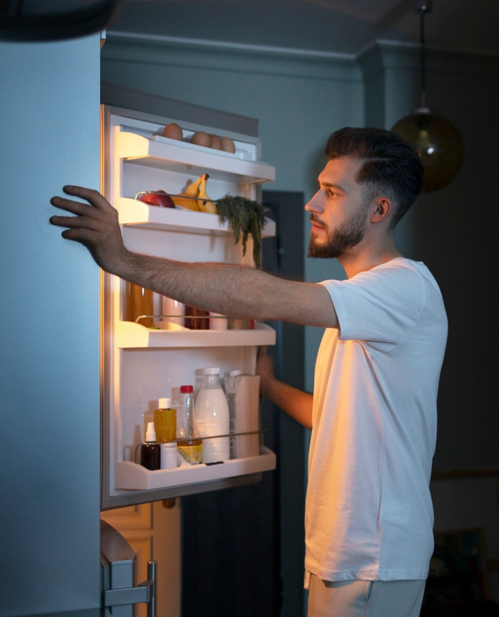 Man opening the fridge at night.